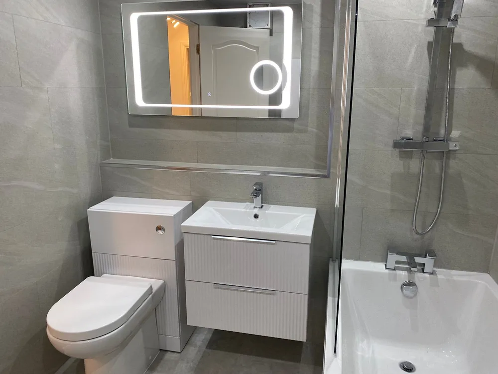 Finished bathroom with a ribbed wall-hung vanity and LED mirror