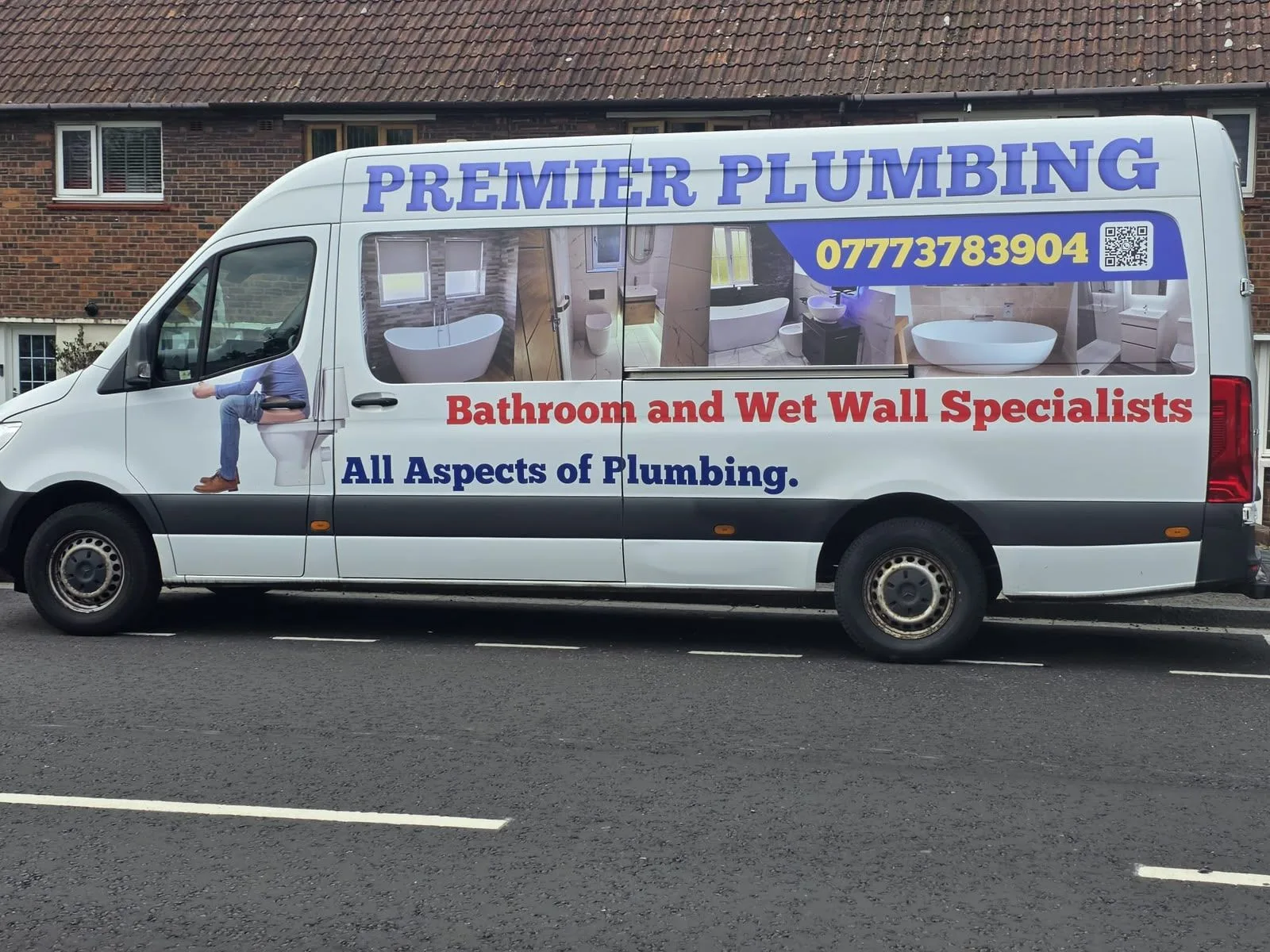 The Premier Plumbing van, signwritten with the phone number and photographs of finished bathrooms